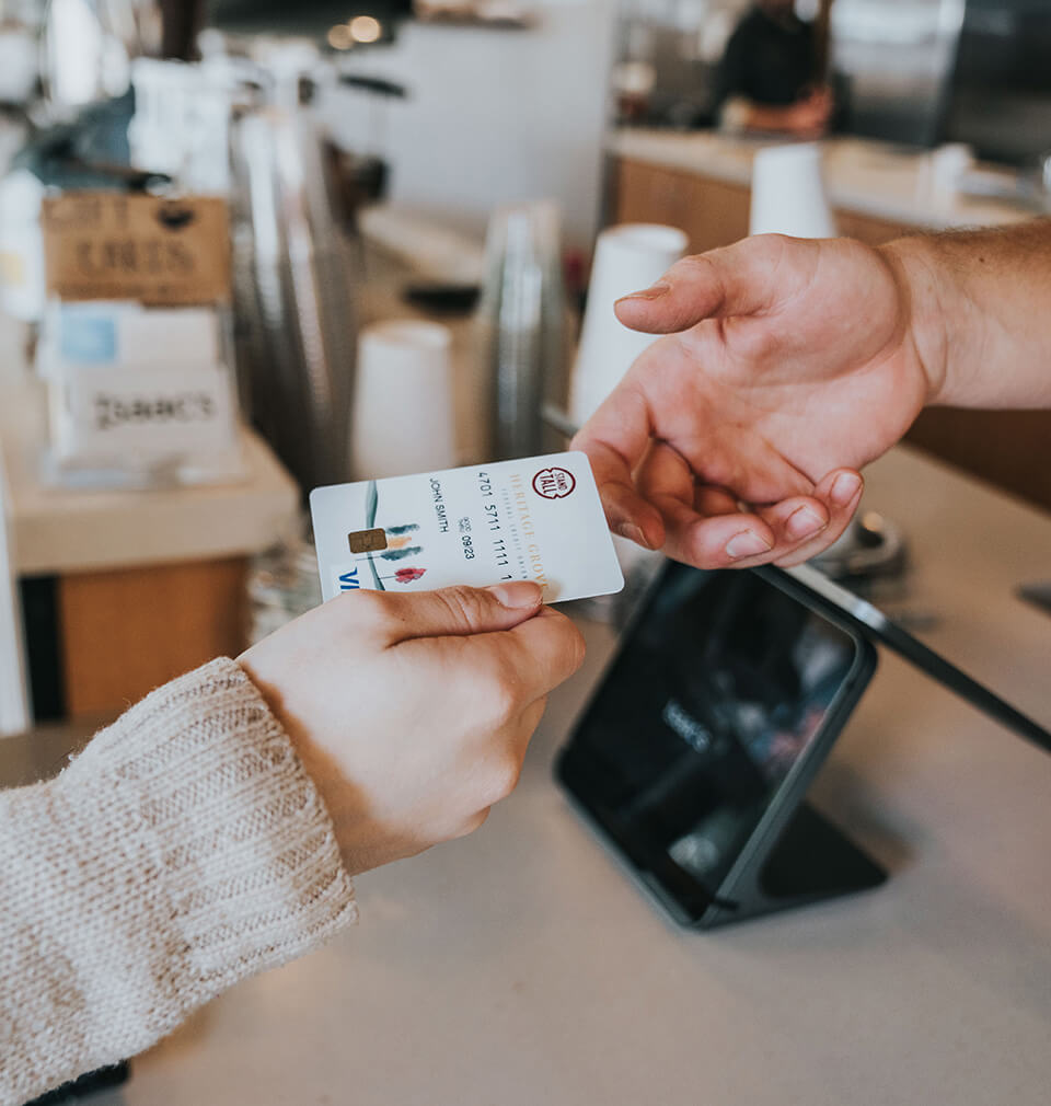 a hand gives another hand a Heritage Grove VISA credit card