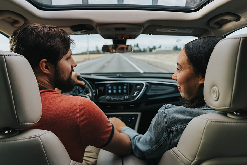 man and woman hold hands while driving down the road