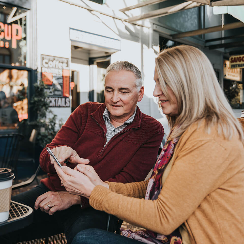 an older man points to something on a phone an older woman is holding