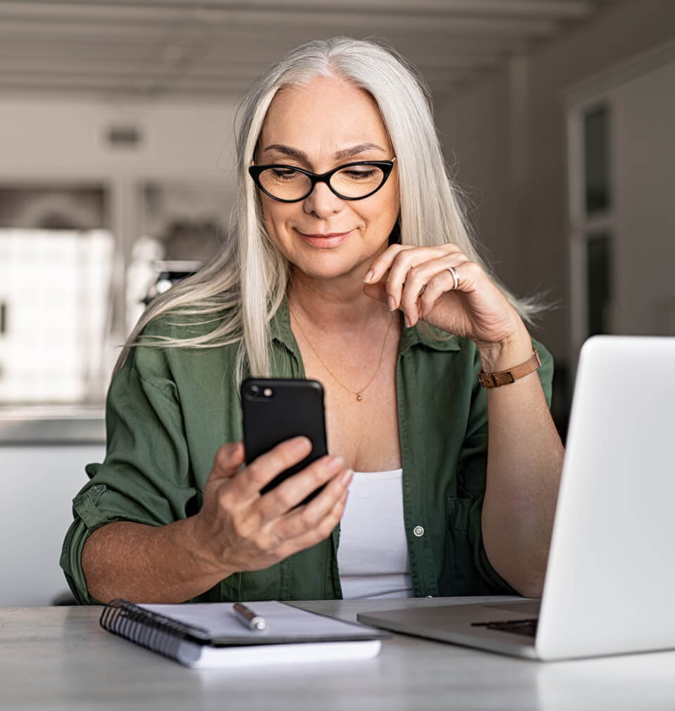 An older white woman looking at her phone