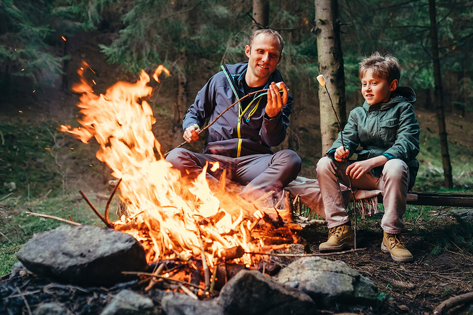 a father and son roast marshmallows at a campsite