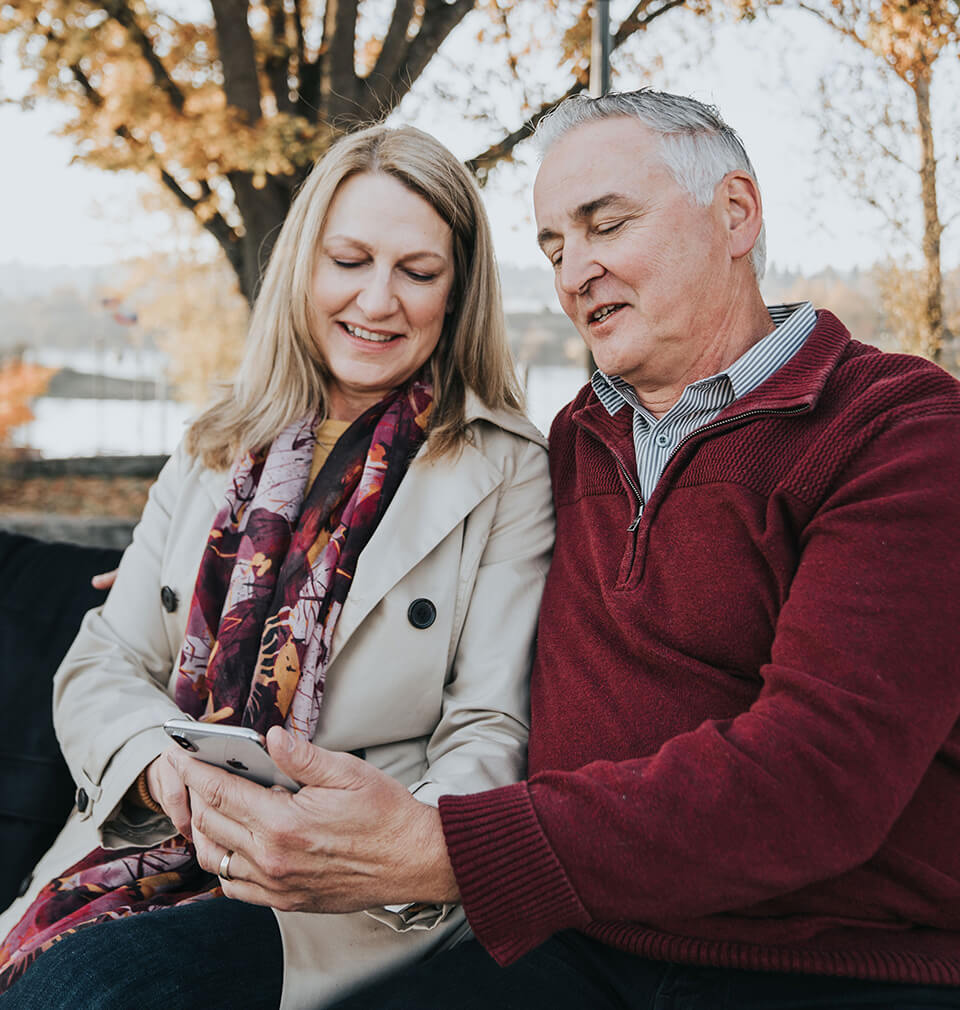 an older couple stare at their phone in bemusement