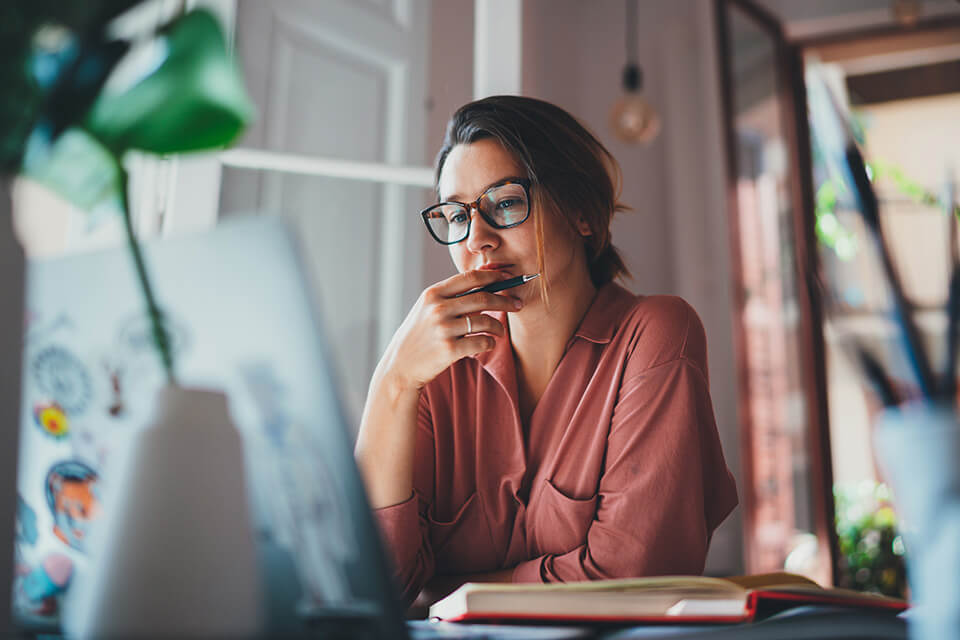 A middle-aged woman stares pensively at her computer