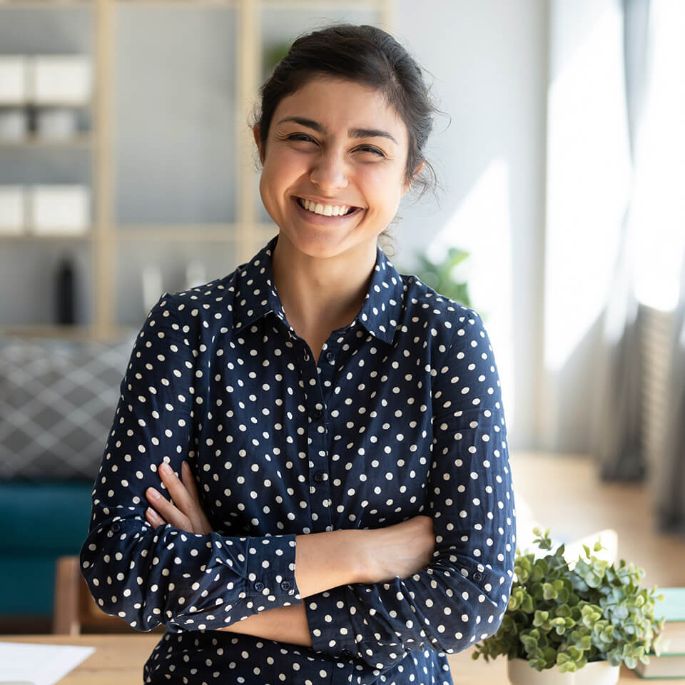 a smiling woman in a blue polka dot blouse