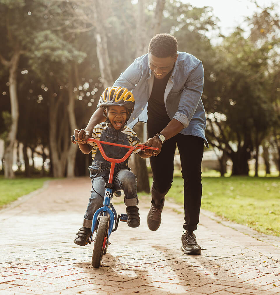 a father helping his son learn to ride a bike