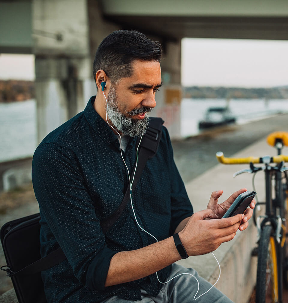 a middle aged man listens to headphones on his mobile phone