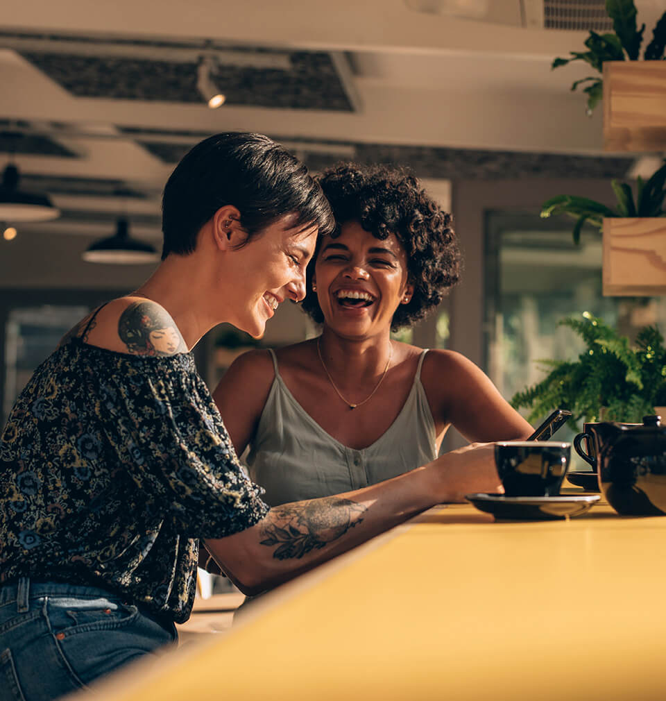 two women laughing over coffee