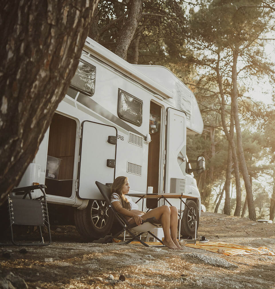 woman relaxes near an RV