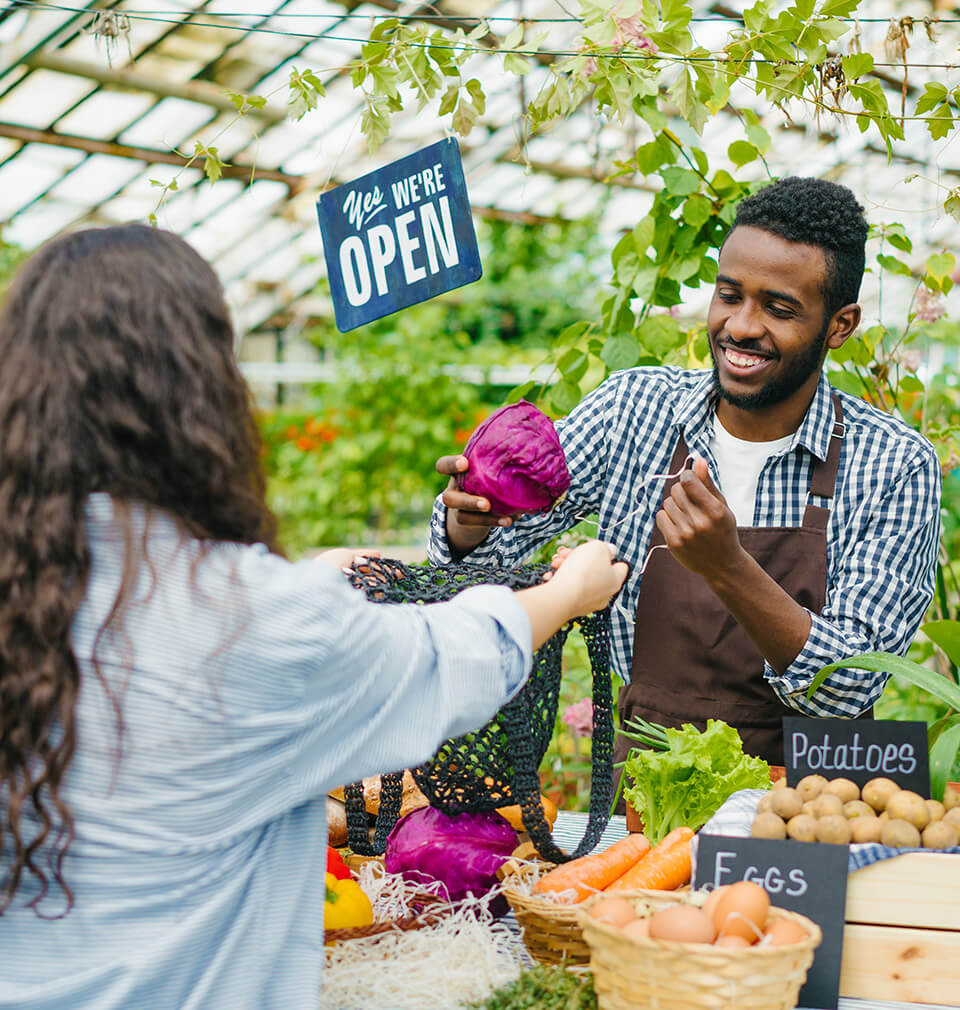 a man gives a woman some vegetables at a farmer's market