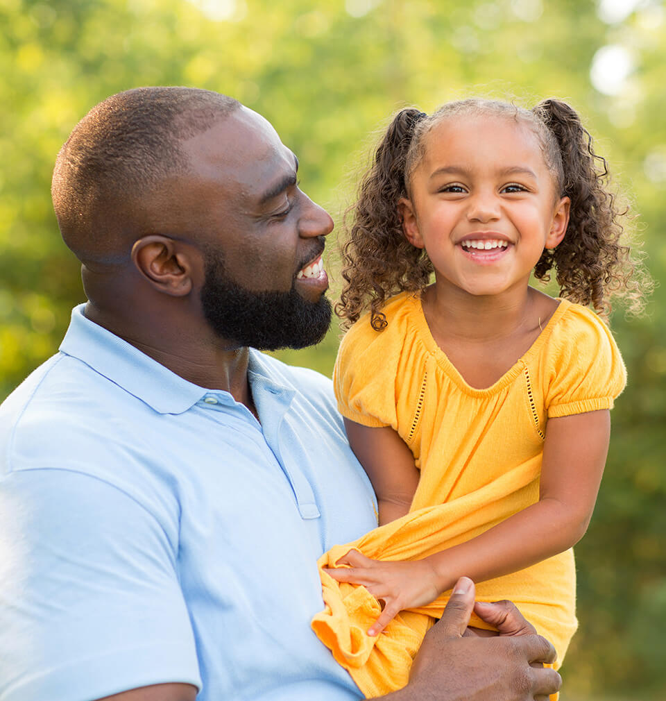 a father smiles at his daughter in a yellow dress