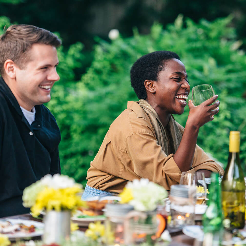 a white man and black woman laughing over wine